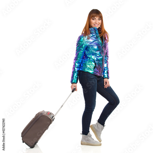 Happy Young Woman In Winter Clothes Is Walking With Trolley Bag