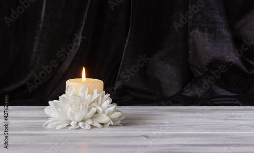The concept of remembrance, funerals, and condolences. Candle and white flowers, free space for text