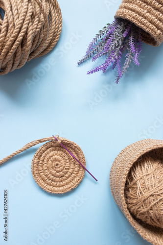 The knitted part of the basket made of jute rope and a crochet hook. Hobbies, needlework, organization of space.