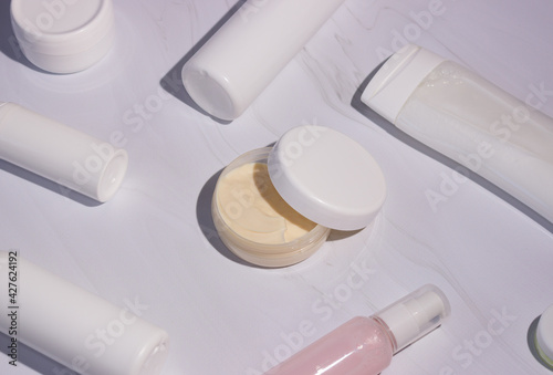 Cream in a jar with an open lid and bottles for cosmetics. shadows