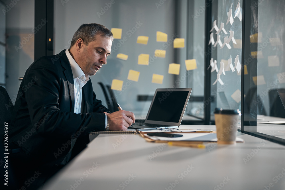 Serious businessman writing in notebook at work Serious businessman writing in notebook at work
