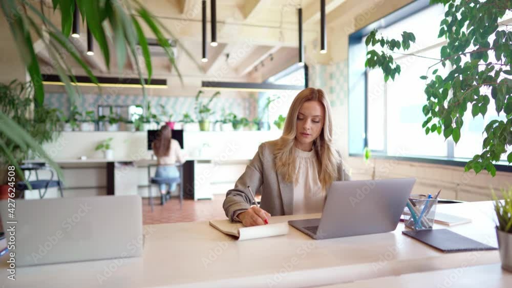 Young businesswoman in formal suit working at the table in modern open space office Young businesswoman in formal suit working at the table in modern open space office