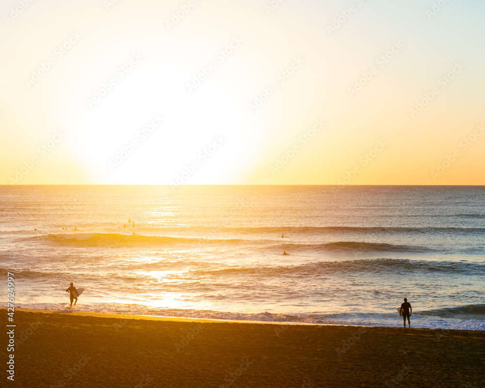two male surfers on the beach with their surfboard on their way to get into the water to surf at sunrise