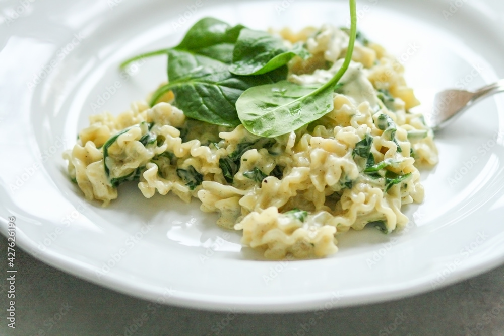 Mafalde Pasta with Mascarpone cheese sauce and spinach on a white plate with a silver fork