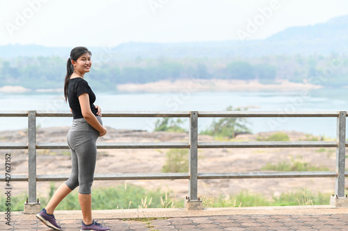 Portrait of young Asian pregnant woman walking and workout in the park.