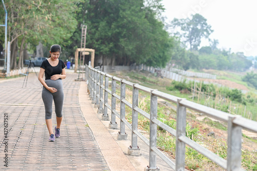 Portrait of young Asian pregnant woman walking and workout in the park.