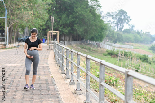 Portrait of young Asian pregnant woman walking and workout in the park.