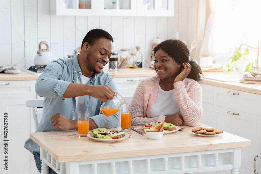 Loving African American Family Of Two Having Breakfast In Kitchen