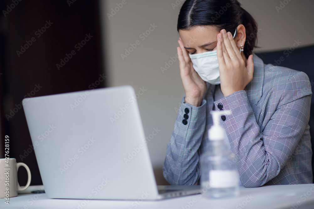 Sick, ill unhealthy female employee working in workplace in office and wearing surgical hygienic mask on her face. Concept of corona virus or covid-19 Sick, ill unhealthy female employee working in workplace in office and wearing surgical hygienic mask on her face. Concept of corona virus or covid-19