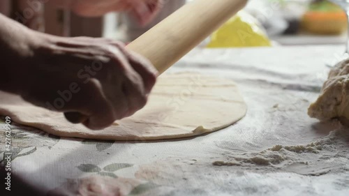 A woman rolls out the dough with a rolling pin.Hands close up, slow motion.