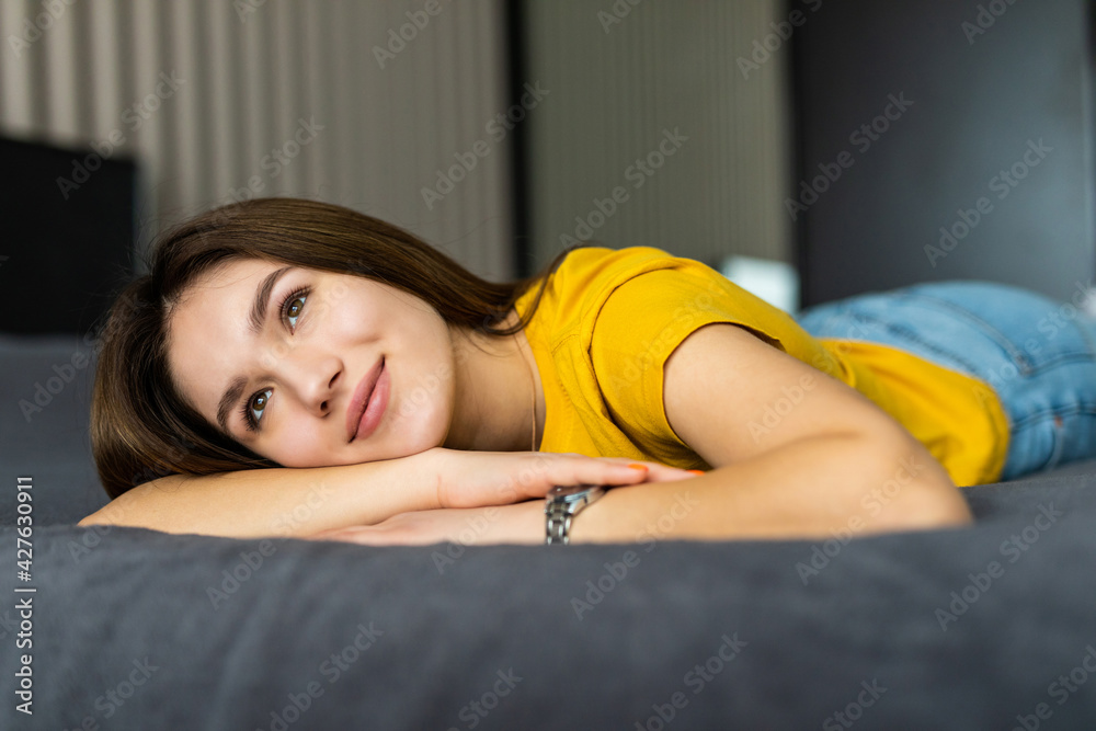 Pure beauty. Beautiful young woman looking at camera while lying on the bed at home Pure beauty. Beautiful young woman looking at camera while lying on the bed at home
