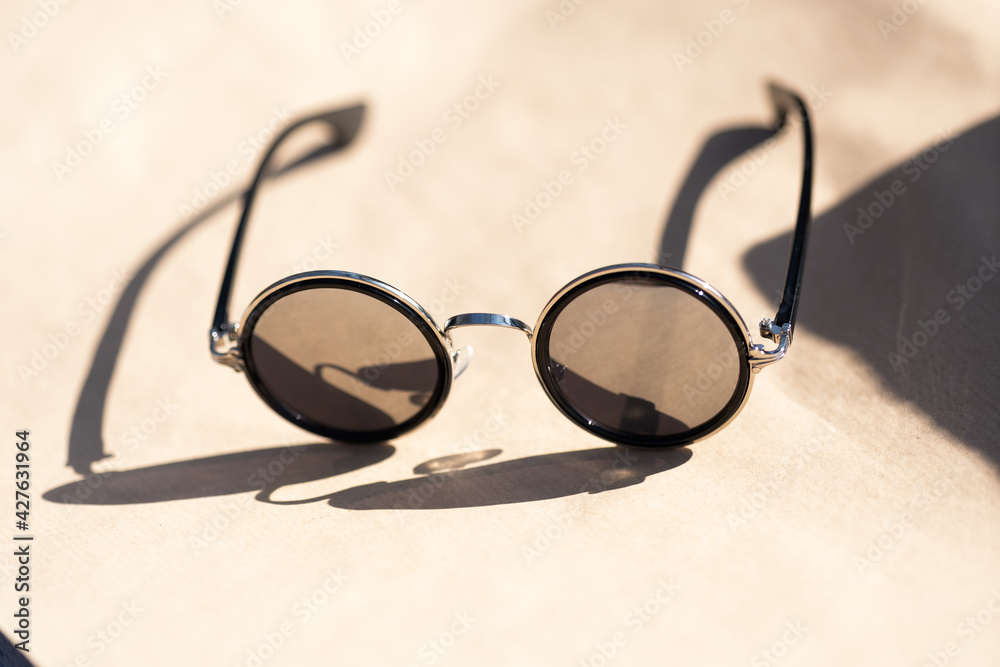Classic sunglasses design with silver round lenses shoot in a sunny day of summer closeup. Selective Focus. High quality photo Classic sunglasses design with silver round lenses shoot in a sunny day of summer closeup. Selective Focus. High quality photo