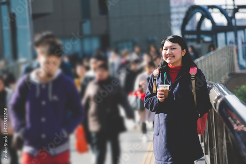Travelers holding a cup of coffee stand watch Osaka Umeda district on the overpass with happiness in winter. © 2p2play