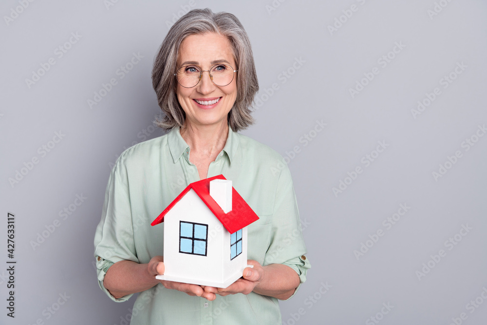 Photo of happy good mood lovely charming woman in glasses hold little house relocation isolated on grey color background