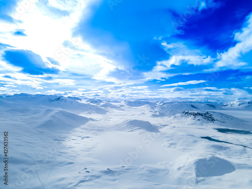Spectacular panoramic view over snowcapped mountain peaks, ridges and frozen highland tundra in Jotunheimen, Norway.