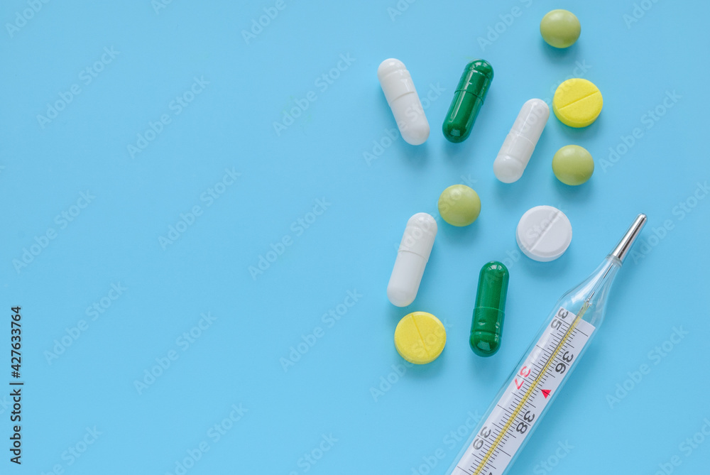 Mercury thermometer medical mask and pills on blue background Mercury thermometer medical mask and pills on blue background