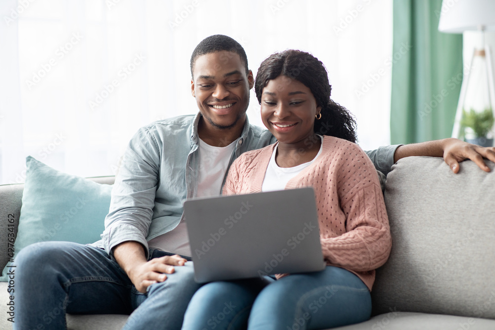 Happy african american family sitting on couch, using laptop Happy african american family sitting on couch, using laptop