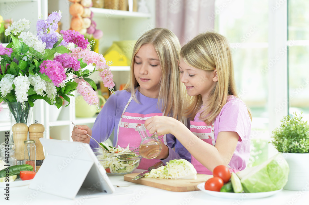 Two girls in pink aprons preparing salad Two girls in pink aprons preparing salad