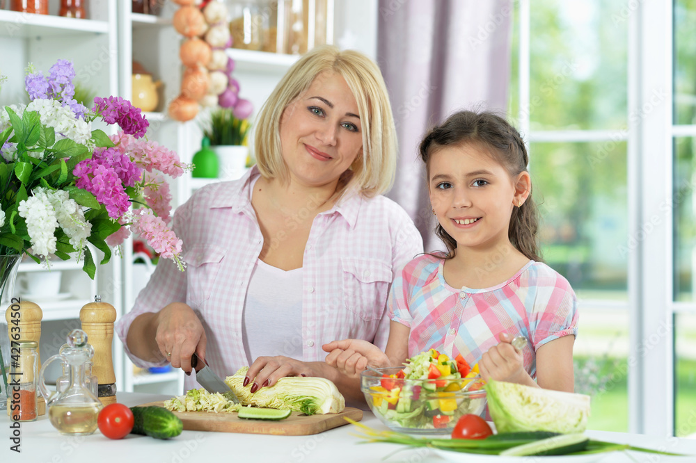 Happy mother and daughter cooking together at kitchen Happy mother and daughter cooking together at kitchen