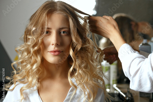 Hair stylist making hairdo to a beautiful woman