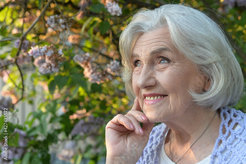  senior beautiful happy woman posing by lilacs in park
