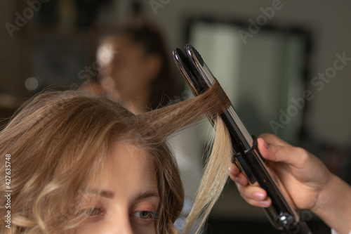 Hair stylist making hairdo with styling iron