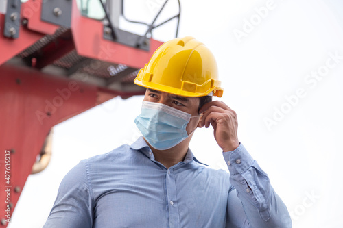 young businessman wearing face mask to protect coronavirus or covid-19 pandemic and pm2.5 bad air pollution from traffic and manufacturing industrials in the city.