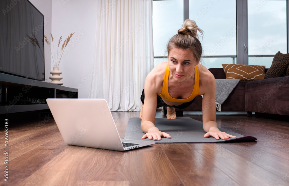 Woman doing online yoga at home. Female trener teaches asana in video conference. Health care, authenticity, sense of balance and calmness. - obrazy, fototapety, plakaty 