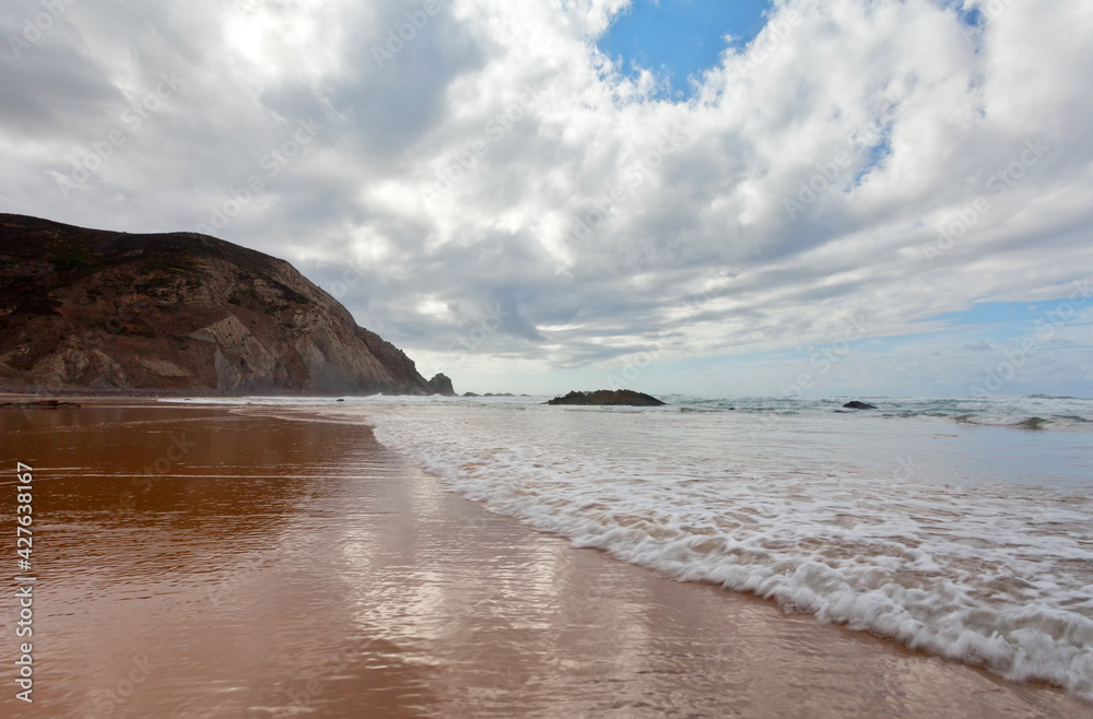 Portugal. The sandy Praia da Castelejo beach in the Algarve on the Atlantic coast. Picturesque seascape. Natural seaside background. Summer travel and recreation Portugal. The sandy Praia da Castelejo beach in the Algarve on the Atlantic coast. Picturesque seascape. Natural seaside background. Summer travel and recreation