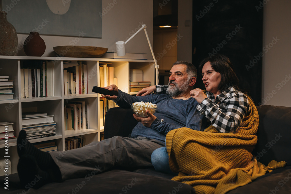 middle age couple watching television at home. evening scene
