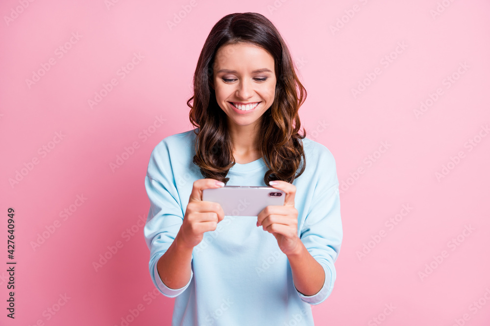 Photo of young attractive woman happy positive smile play game smartphone isolated over pastel color background Photo of young attractive woman happy positive smile play game smartphone isolated over pastel color background