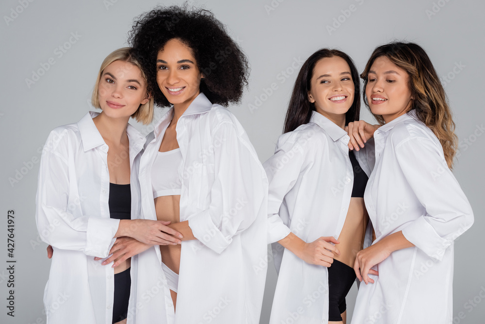 happy multiethnic friends in underwear and white shirts embracing isolated on grey happy multiethnic friends in underwear and white shirts embracing isolated on grey