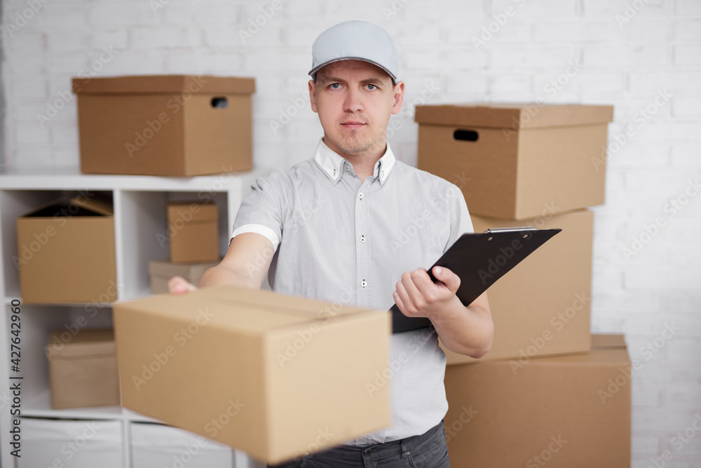 Deliveryman holding a clipboard and giving a box in warehouse Deliveryman holding a clipboard and giving a box in warehouse