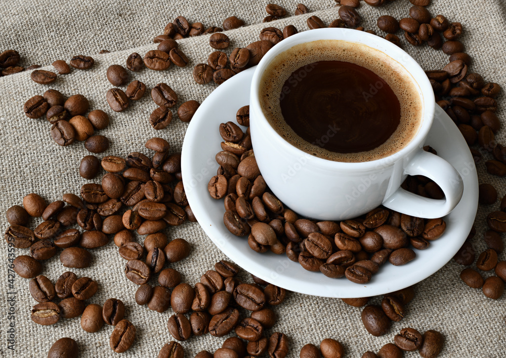 Coffee cup and a scattering of coffee beans Coffee cup and a scattering of coffee beans