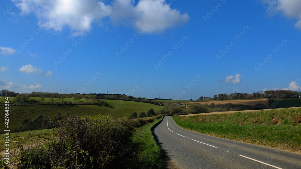 Clear rural roads leading in to the distance. With bright spring sunshine blue sky and fluffy clouds