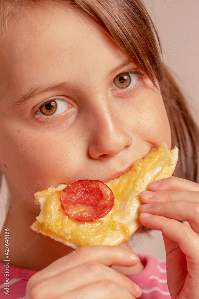 It's really delicious! Happy beautiful young girl is eating a piece of pizza. Selective focus. It's really delicious! Happy beautiful young girl is eating a piece of pizza. Selective focus.