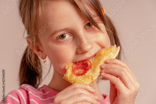 It's really delicious! Happy young girl is eating a piece of pizza.