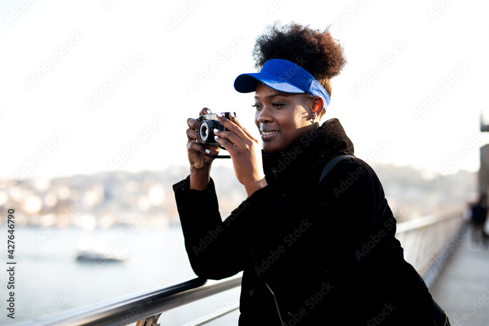 Obraz premium Young female traveler with camera. Beautiful african woman in the city