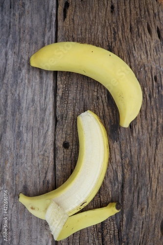 Half peeled banana tropical fruit on wood background or texture