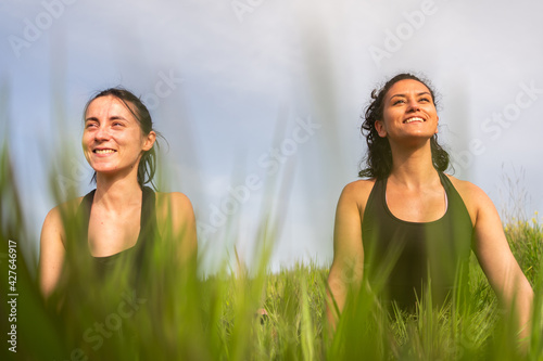 two girls are practicing yoga in a field in nature under the sun. photo