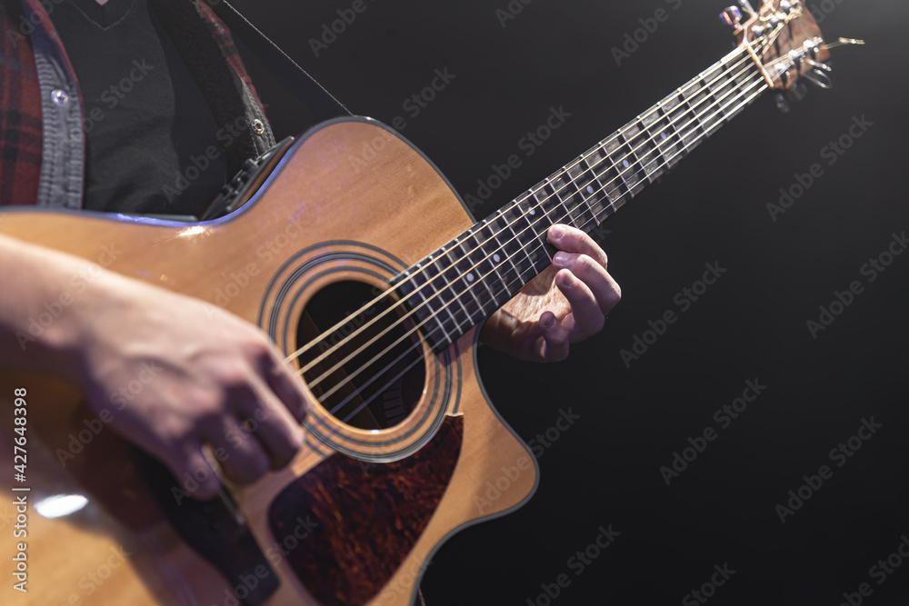 Guitarist playing acoustic guitar in the dark.