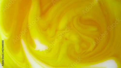 Cosmetic milk and Carotene. .White liquid mixed with orange beta carotene solution..Skincare product for face and body..Close up. Rotation. Abstract background..Top view. Beauty concept.