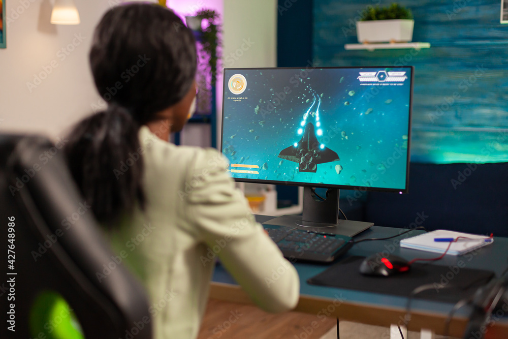 Pro african gamer playing space shooter with wireless joystick at night. Competitive cyber player woman performing videogame tournament use professional joystick. Pro african gamer playing space shooter with wireless joystick at night. Competitive cyber player woman performing videogame tournament use professional joystick.