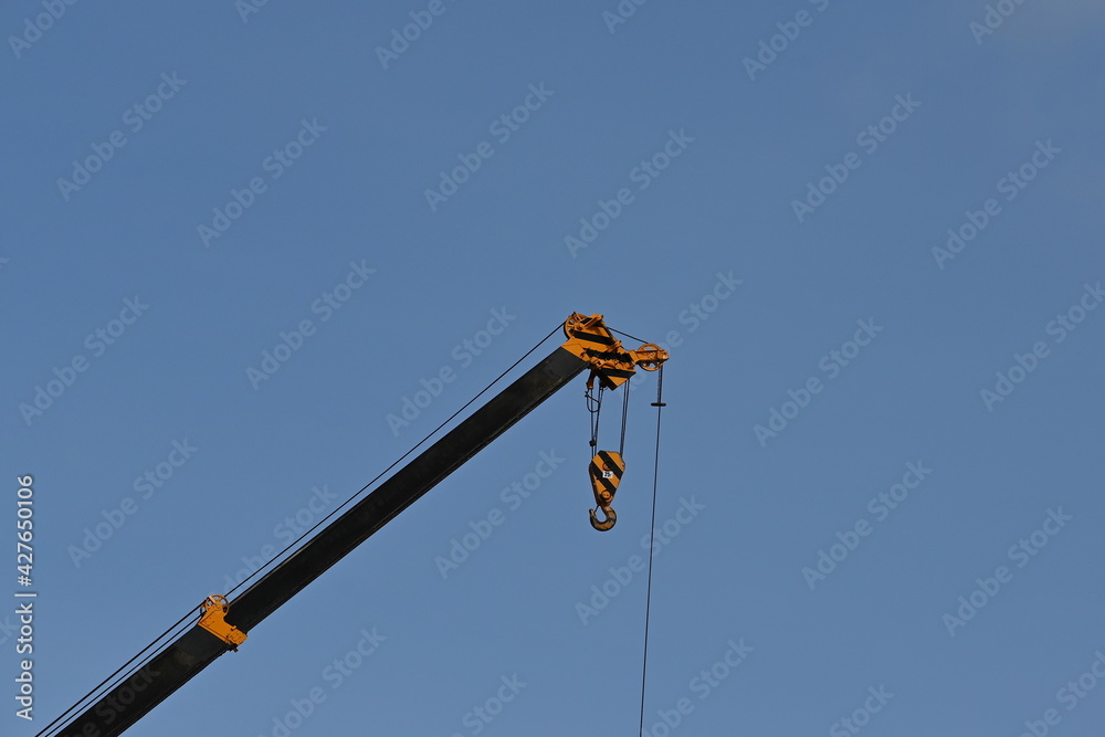 Hooks with steel crane slings and arms painted in yellow and black on a blue sky background. Used for lifting large objects or items weighing up to 25 tons.
Hooks with steel crane slings and arms painted in yellow and black on a blue sky background. Used for lifting large objects or items weighing up to 25 tons.