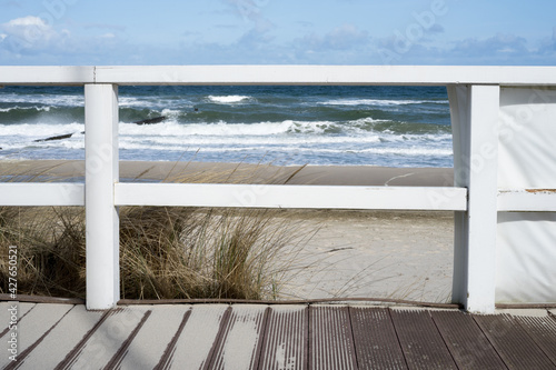 Fototapeta Naklejka Na Ścianę i Meble -  White wooden veranda on the Baltic Sea beach with waves, sand, blue sky and sun