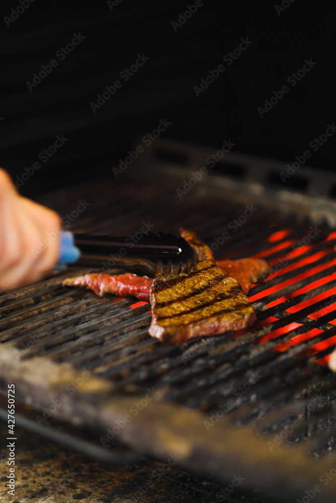 Cooking meat and 2d on fire. Grill and barbecue. Chef cats steak in the restaurant.