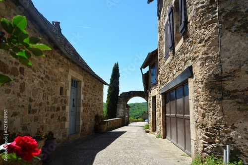 The narrow and picturesque alleys of Najac. Old stone houses decorated with flowers. South France. 