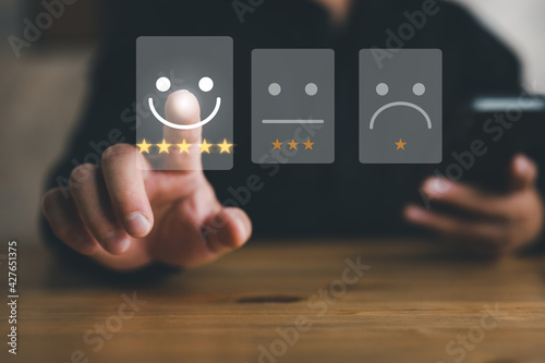 Customer service evaluation concept. Businessman pressing face smile emoticon and five star show on virtual screen.