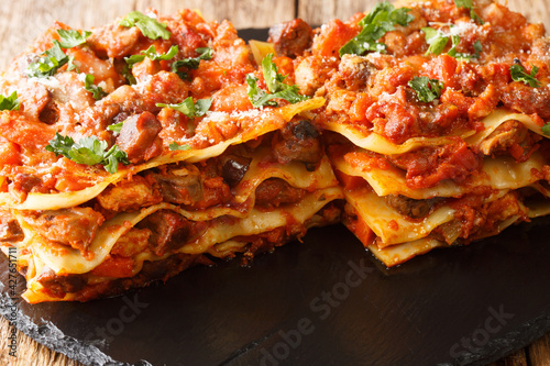 Italian Vincisgrassi or vincesgrassi, is a typical Marche pasta dish similar to lasagne al forno closeup in the slate board on the table. horizontal