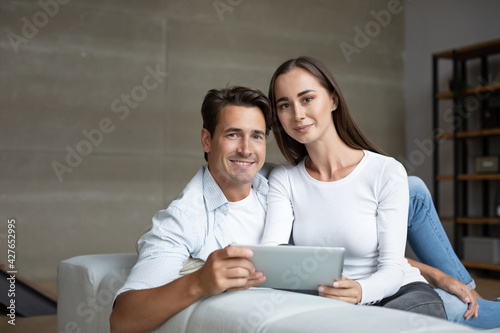 Happy young family using digital tablet together on the couch